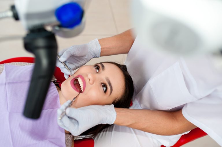 Beautiful girl treats teeth in dentistry.