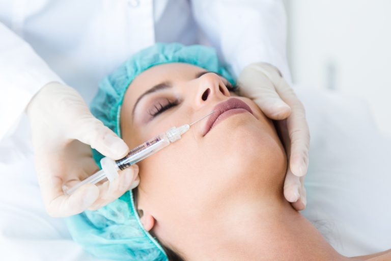 Portrait of beautiful young woman getting botox cosmetic injection in her face.