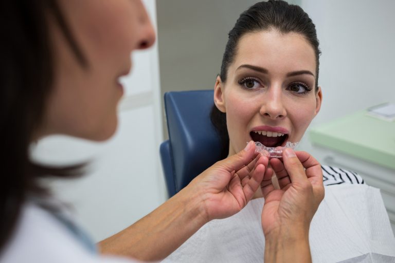 Dentist assisting a patient to wear orthodontic silicone invisible braces