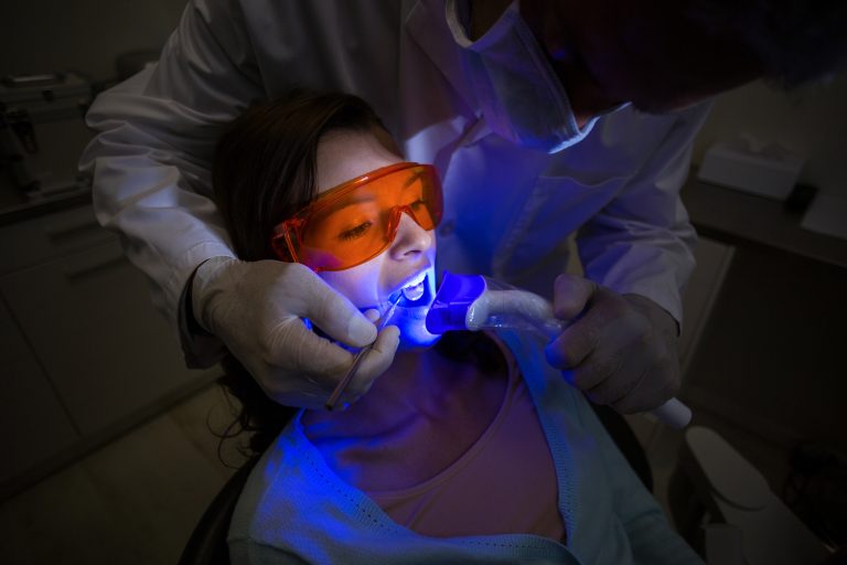 Dentist examining a female patient with dental tool at dental clinic