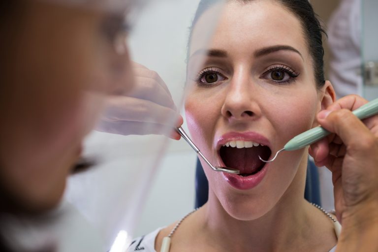 Dentist examining a female patient with tools at dental clinic