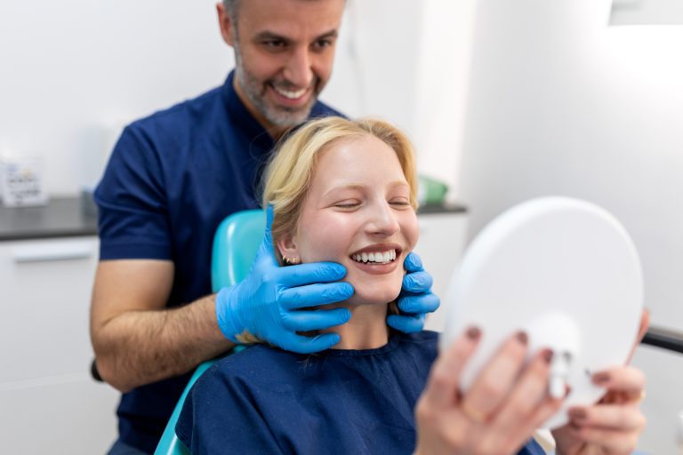 European young woman smiling while looking at mirror in dental clinic