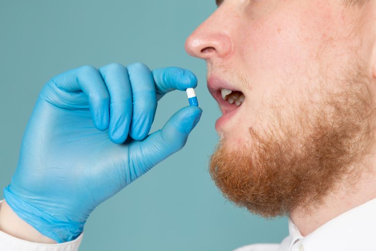 front-view-young-man-taking-pills-blue-gloves